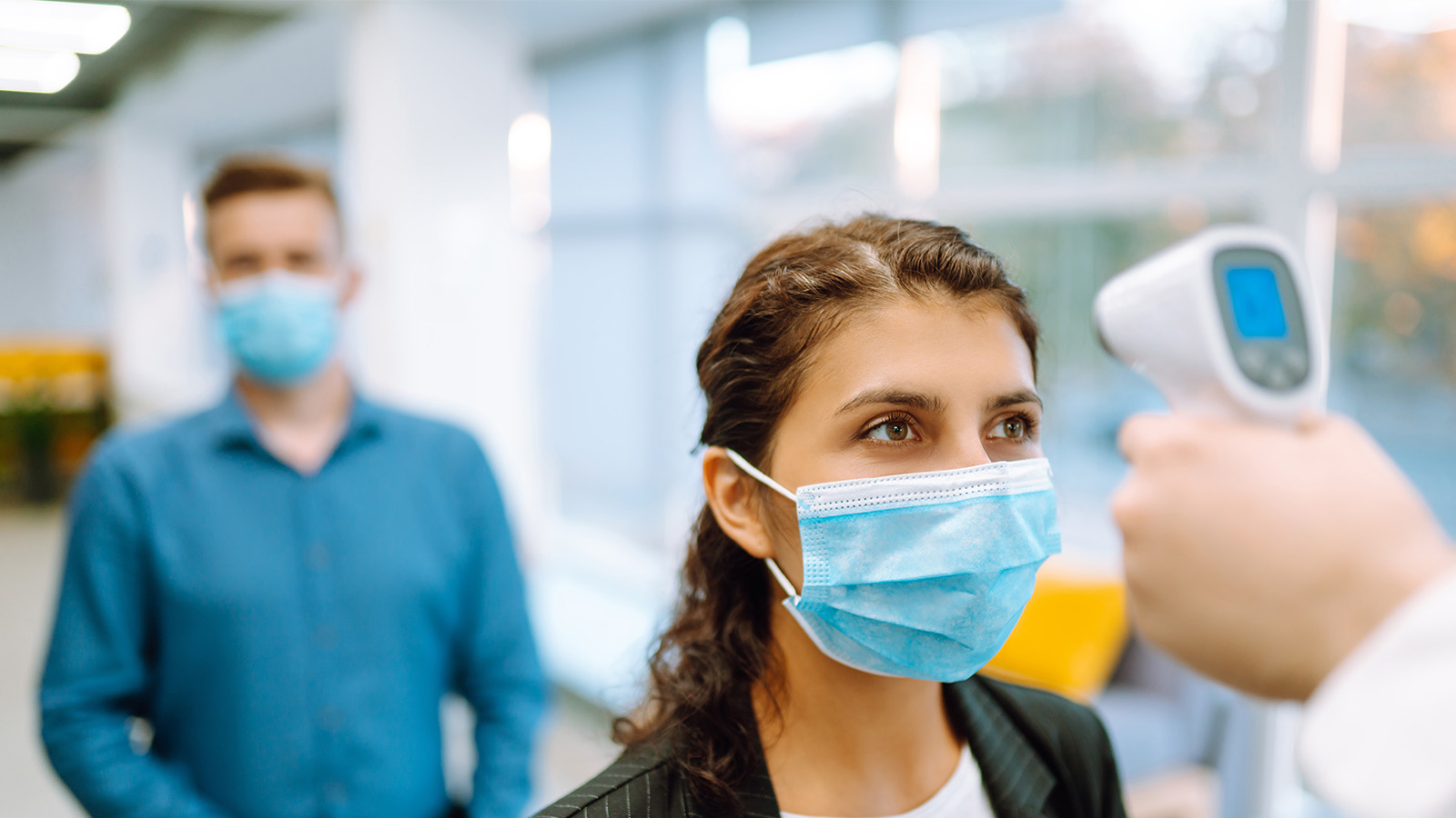 Checking the temperature of a person with a mask on using a digital thermometer.
